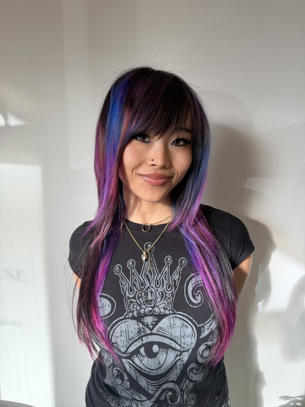 Joon, alternative hair stylist at The Parlour SCV, wearing her own long layered cut in blue, violet and magenta